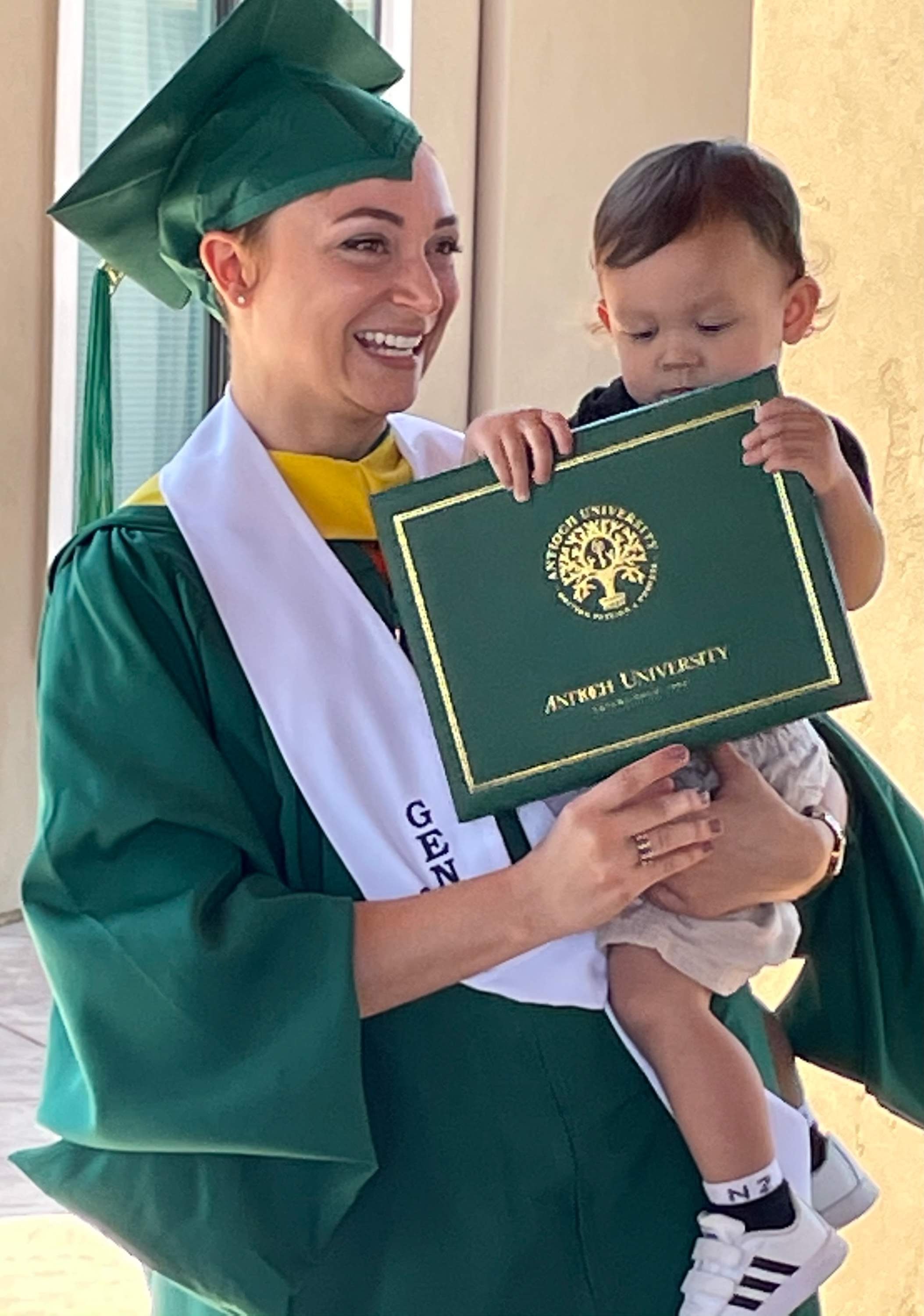 Kristy holding a baby and diploma folder