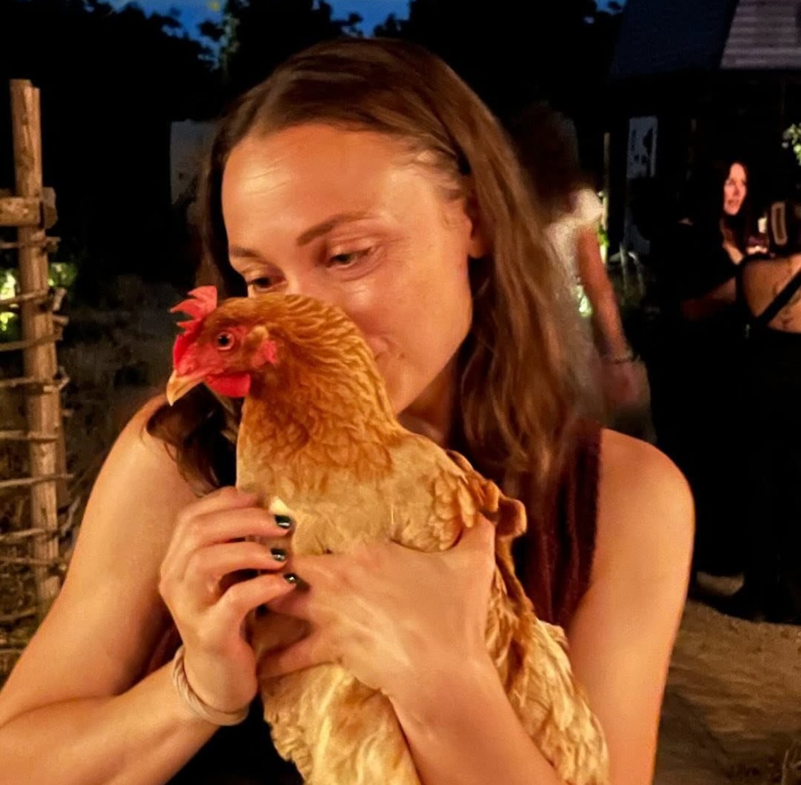 Kristy holding a brown chicken outdoors